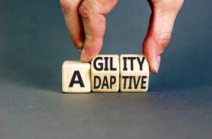 Agility and adaptive symbol. Concept words Agility and Adaptive on wooden cubes. Beautiful grey table grey background. Businessman hand. Business agility and adaptive concept.