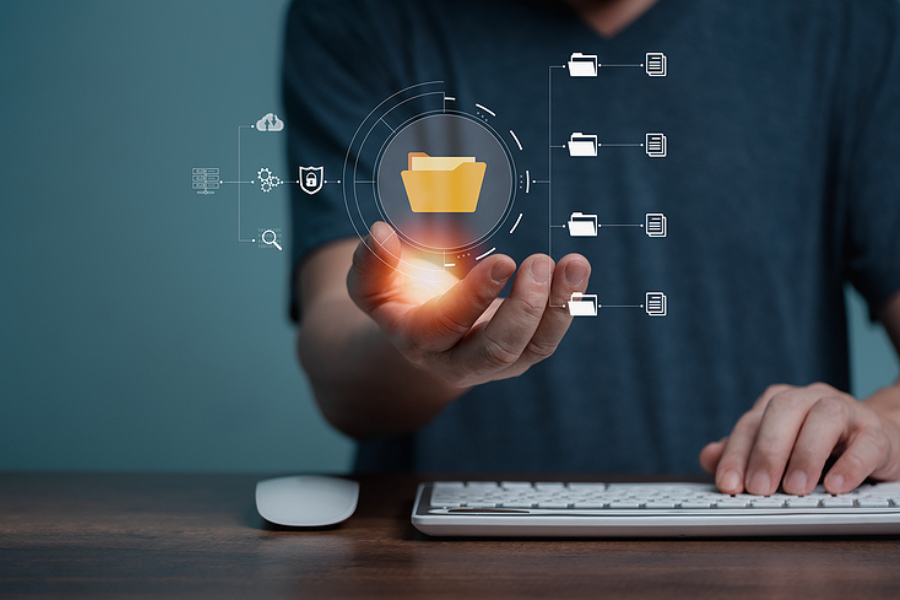 person at computer keyboard, holding an overlay of folders in palm to suggest document management systems