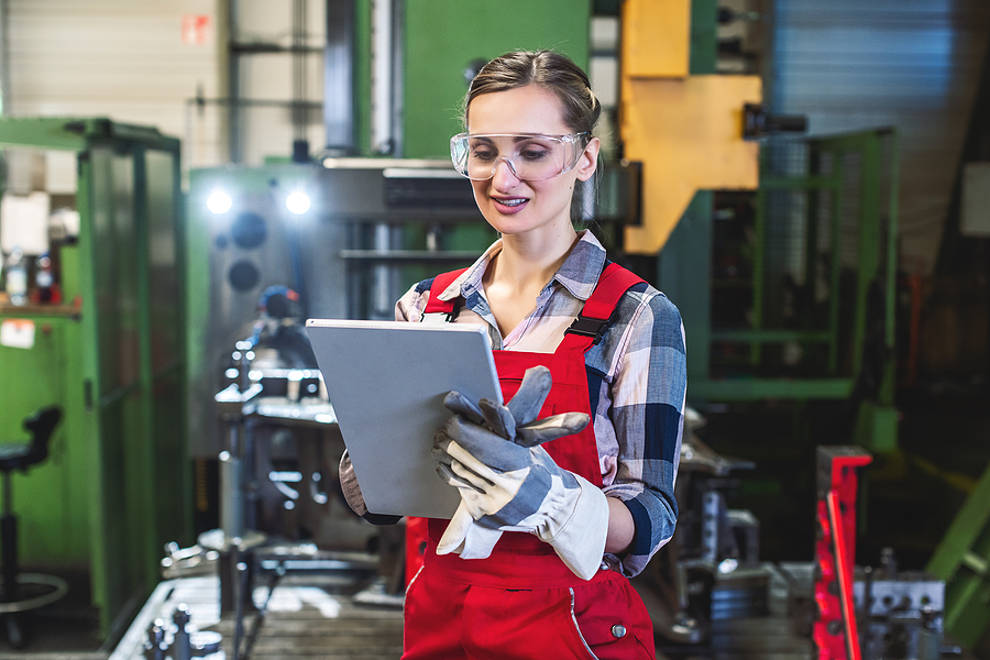 worker with tablet computer in front of machine to convey manufacturing ERP system